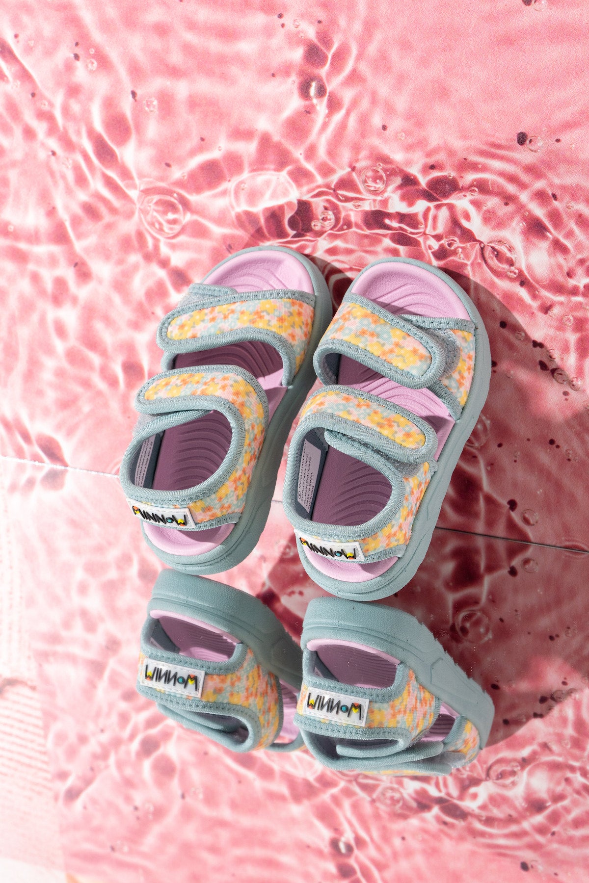 Yellow pink and green floral sandals on a pink water background